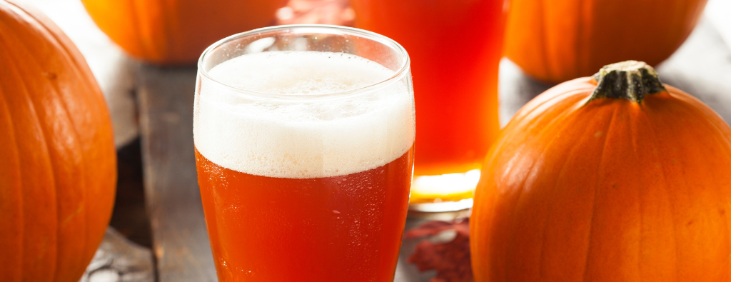 glass of beer in front of pumpkins