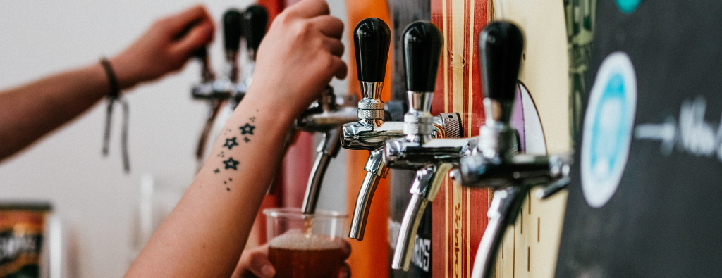 Two hands pouring beer from a spout